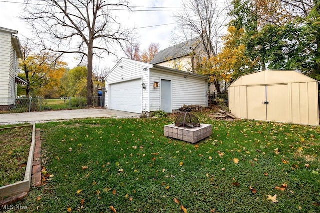 view of yard featuring a garage, a fire pit, and a shed