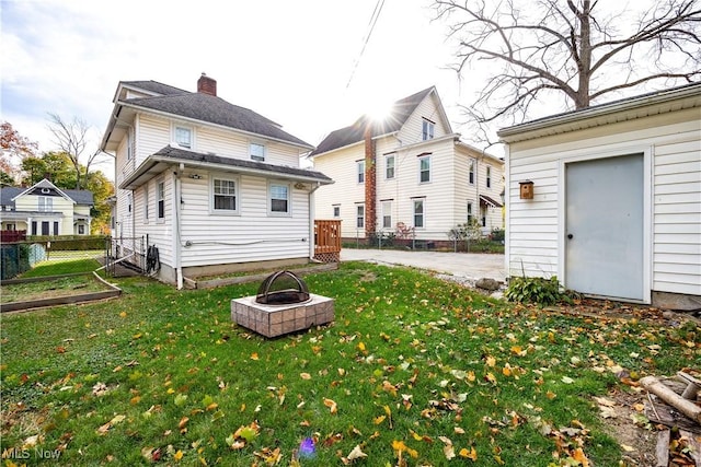 rear view of house with a lawn and a fire pit