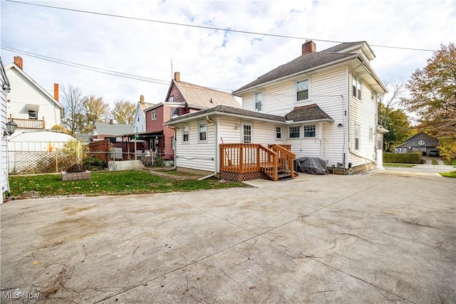 rear view of house with a patio, a lawn, and a wooden deck