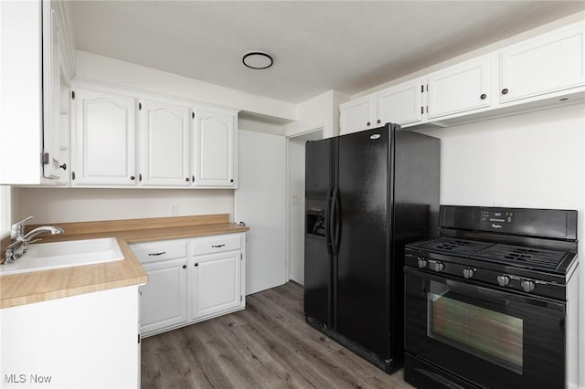 kitchen featuring sink, black appliances, wood-type flooring, and white cabinetry