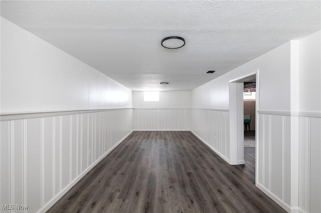 hall featuring a textured ceiling and dark hardwood / wood-style floors