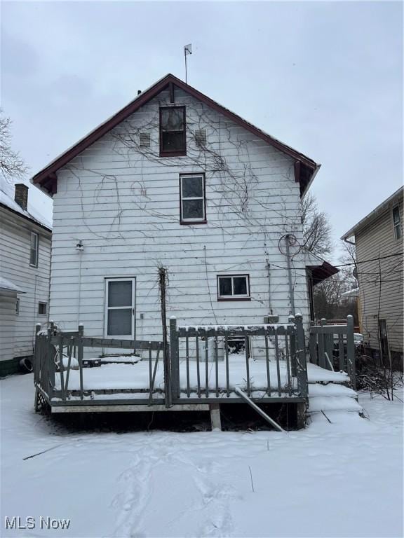 snow covered back of property featuring a deck