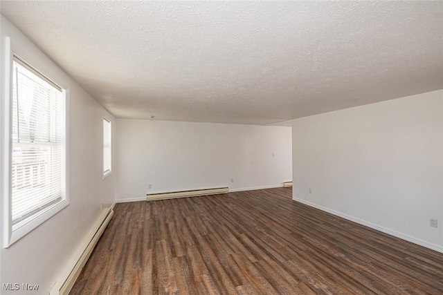 unfurnished room with a textured ceiling, baseboard heating, a healthy amount of sunlight, and dark wood-type flooring