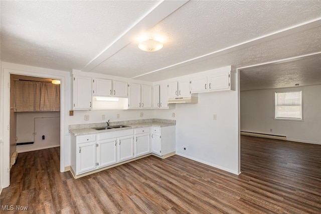 kitchen with a textured ceiling, dark wood-type flooring, a baseboard heating unit, white cabinets, and sink