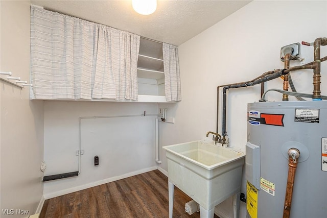 clothes washing area with sink, water heater, a textured ceiling, and dark hardwood / wood-style floors