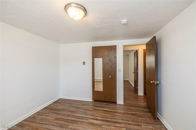 spare room featuring a textured ceiling and dark hardwood / wood-style floors