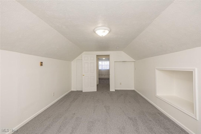 bonus room with a textured ceiling, lofted ceiling, and carpet floors