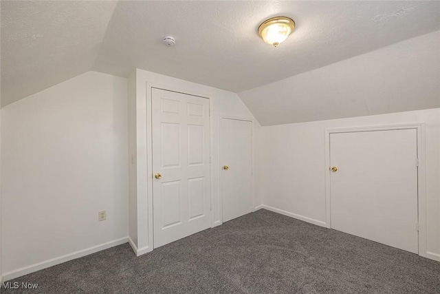 bonus room featuring a textured ceiling, vaulted ceiling, and dark carpet