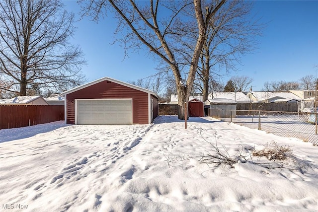 yard layered in snow featuring a garage and a shed