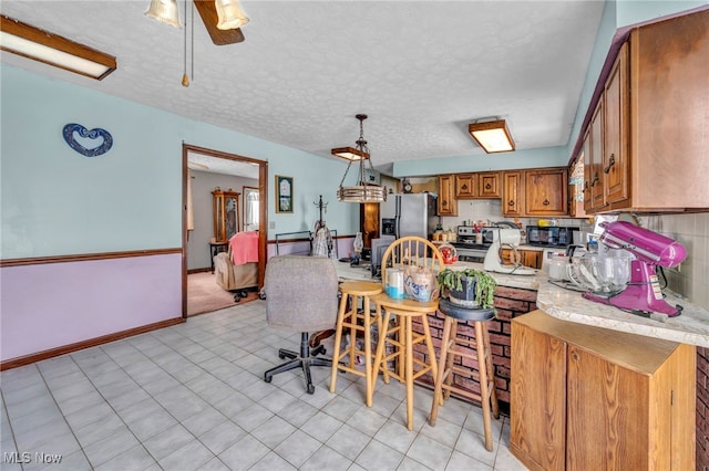 kitchen featuring stainless steel fridge with ice dispenser, a kitchen bar, backsplash, and pendant lighting