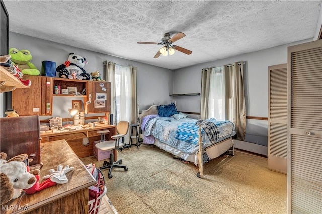 bedroom with ceiling fan, carpet floors, and a textured ceiling