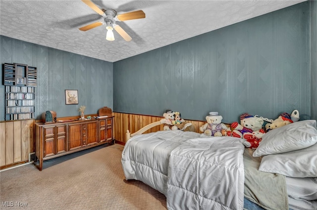 carpeted bedroom with ceiling fan and a textured ceiling