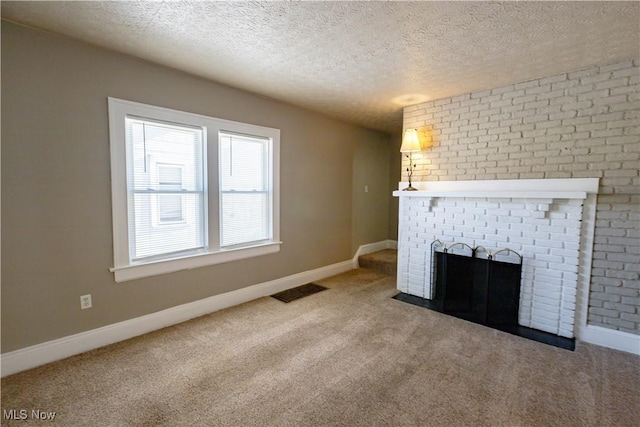 unfurnished living room featuring a brick fireplace, a textured ceiling, and carpet flooring