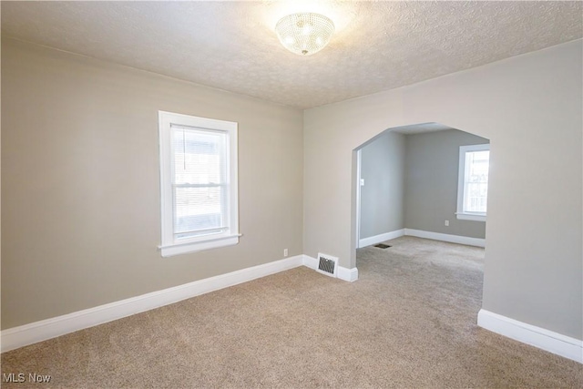 carpeted spare room with a textured ceiling