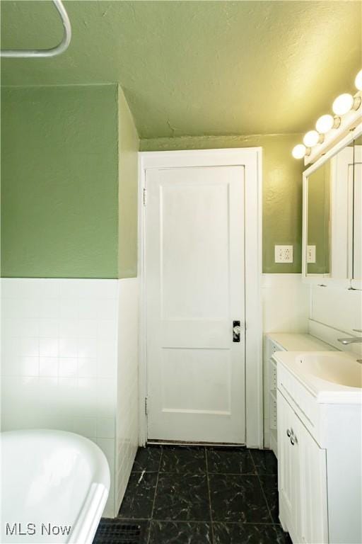 bathroom featuring tile walls, a tub, and vanity