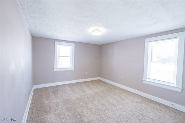 unfurnished room featuring a textured ceiling and light colored carpet