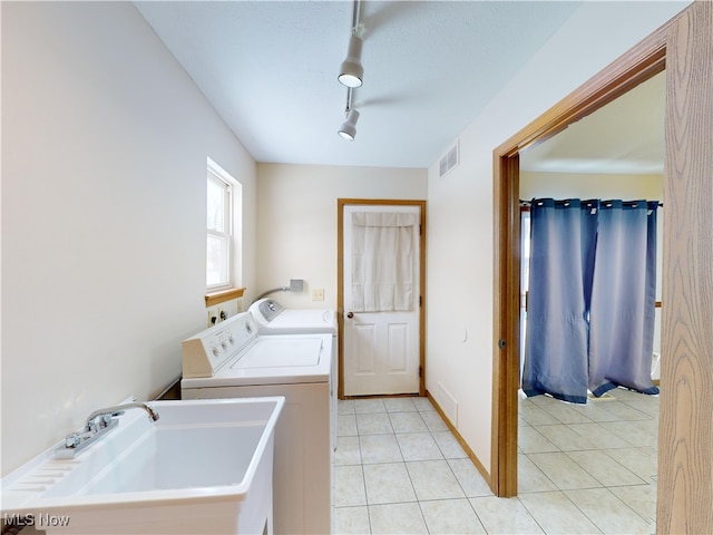 washroom featuring separate washer and dryer, light tile patterned flooring, and sink