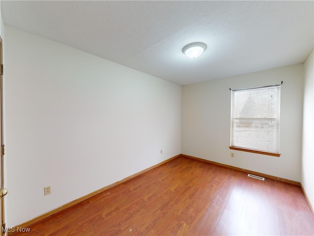 empty room featuring a textured ceiling and hardwood / wood-style flooring