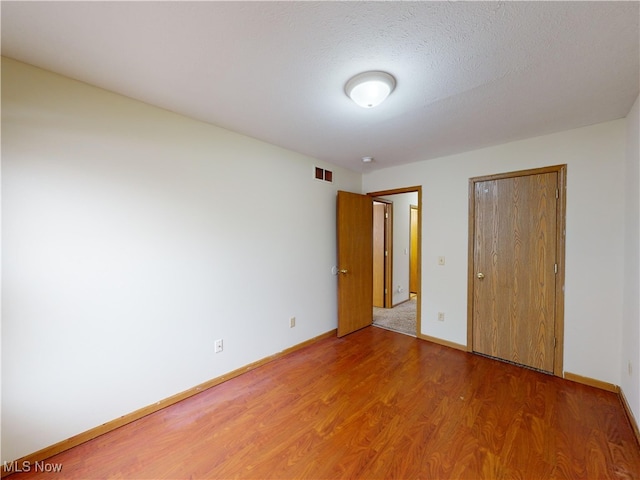 unfurnished bedroom featuring a textured ceiling and hardwood / wood-style floors