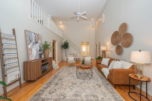 living room featuring ceiling fan, a high ceiling, and wood-type flooring