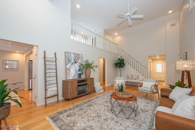 living room featuring a high ceiling, ceiling fan, and wood-type flooring