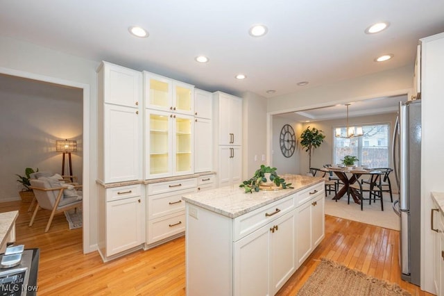 kitchen with hanging light fixtures, white cabinetry, and stainless steel refrigerator