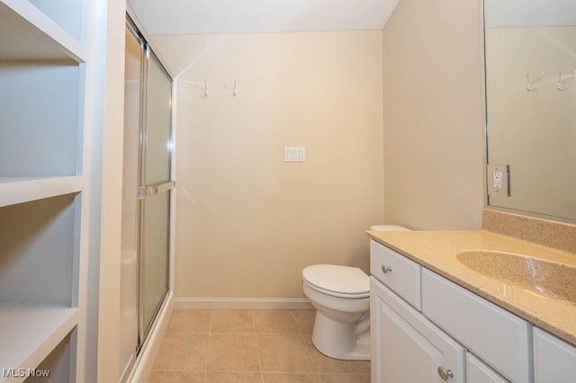 bathroom featuring toilet, tile patterned flooring, walk in shower, and vanity