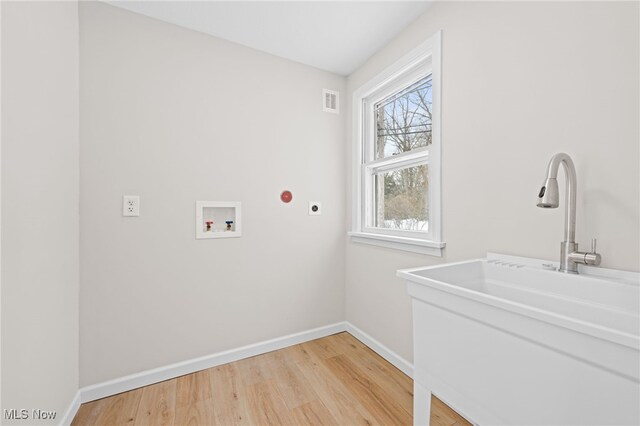 clothes washing area with sink, hookup for a washing machine, electric dryer hookup, and hardwood / wood-style flooring