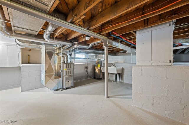 basement featuring water heater, sink, and heating unit