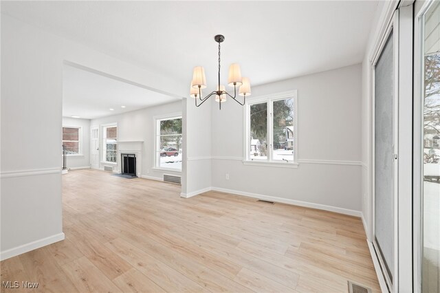 unfurnished living room with a notable chandelier and light hardwood / wood-style flooring