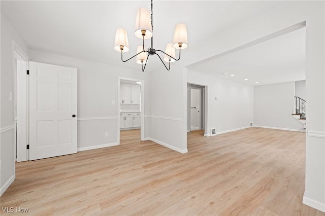 unfurnished room with an inviting chandelier and light wood-type flooring