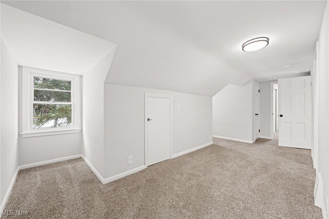 additional living space with light colored carpet and vaulted ceiling