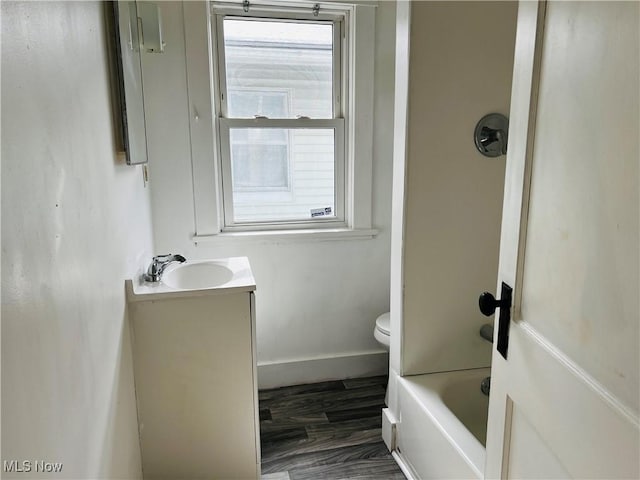 full bathroom with hardwood / wood-style flooring, vanity, toilet, and washtub / shower combination