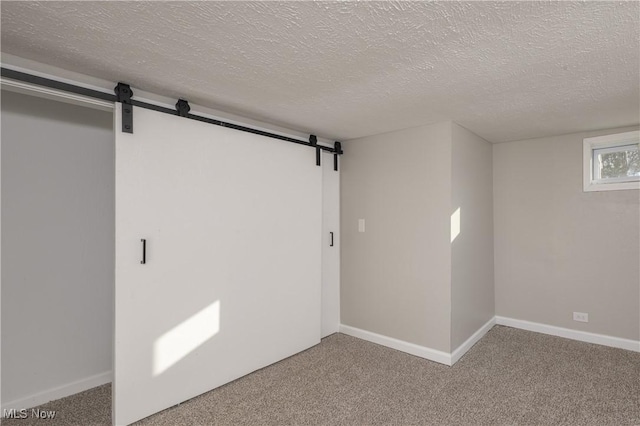 carpeted spare room with a textured ceiling and a barn door