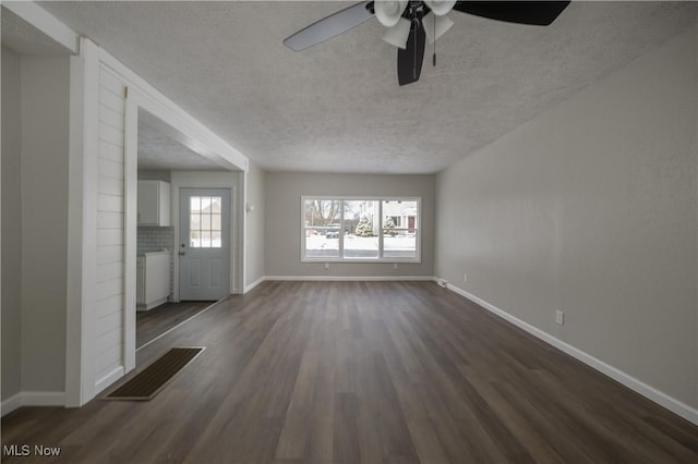 unfurnished living room featuring a brick fireplace, a textured ceiling, ceiling fan, and dark hardwood / wood-style floors