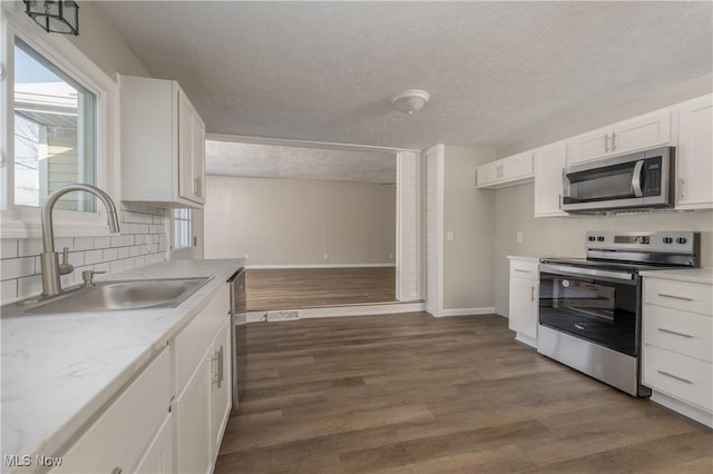 kitchen featuring stainless steel appliances, a textured ceiling, dark hardwood / wood-style floors, sink, and white cabinetry