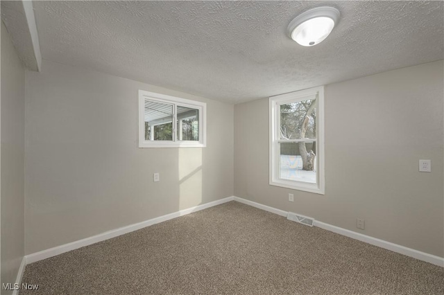 empty room with a textured ceiling and carpet floors