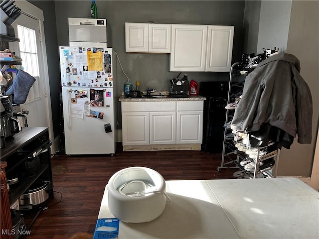 kitchen featuring dark wood-type flooring, white fridge, and white cabinetry