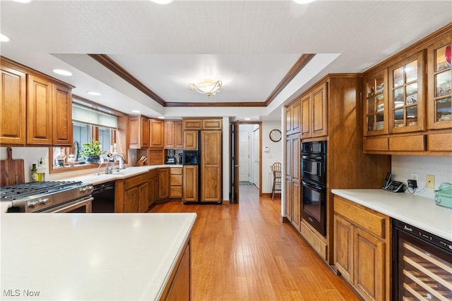 kitchen with a raised ceiling, crown molding, black appliances, and wine cooler