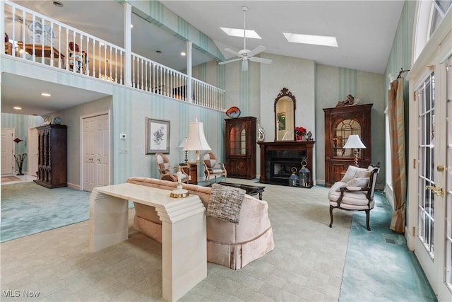 living room featuring ceiling fan, a skylight, and high vaulted ceiling