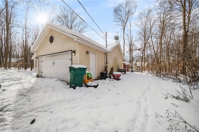 snow covered garage featuring a detached garage