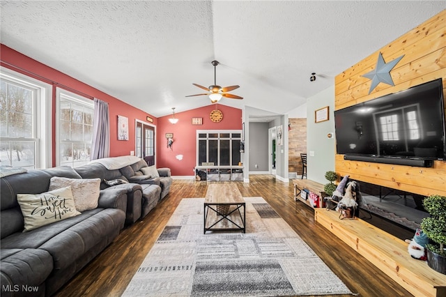 living room with vaulted ceiling, ceiling fan, dark hardwood / wood-style flooring, wooden walls, and a textured ceiling