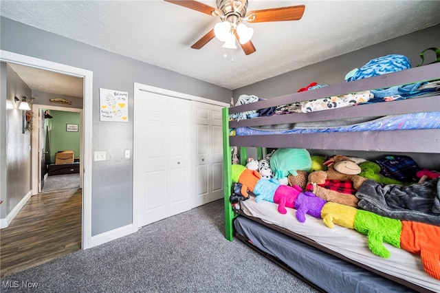 bedroom featuring a textured ceiling, dark colored carpet, ceiling fan, and a closet