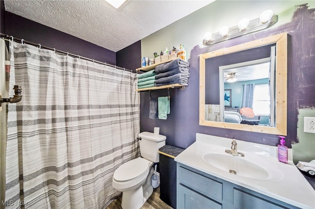 bathroom with toilet, a textured ceiling, ceiling fan, a shower with shower curtain, and vanity