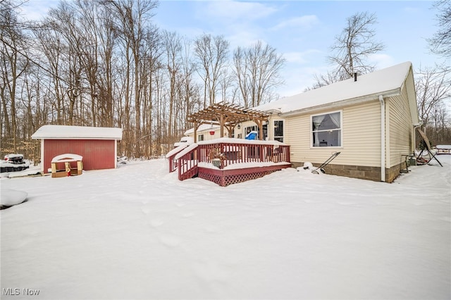 snow covered house featuring a storage unit, an outdoor structure, a deck, and a pergola