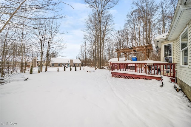 snowy yard with a wooden deck and a pergola