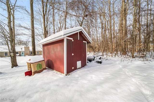 snow covered structure with a storage unit and an outbuilding