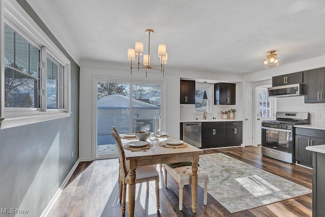 dining room featuring sink, an inviting chandelier, a wealth of natural light, and dark wood-type flooring