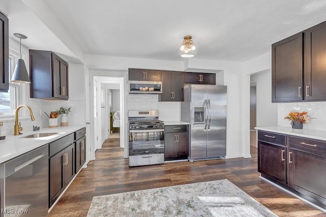 kitchen featuring pendant lighting, stainless steel appliances, dark hardwood / wood-style flooring, dark brown cabinets, and sink