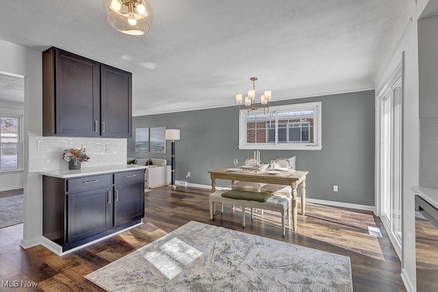 dining area with an inviting chandelier, ornamental molding, and dark wood-type flooring